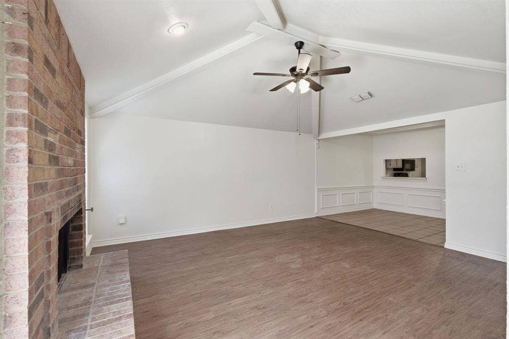 Vaulted ceiling with exposed beams, wood-finish flooring, brick fireplace, recessed lighting, and a ceiling fan