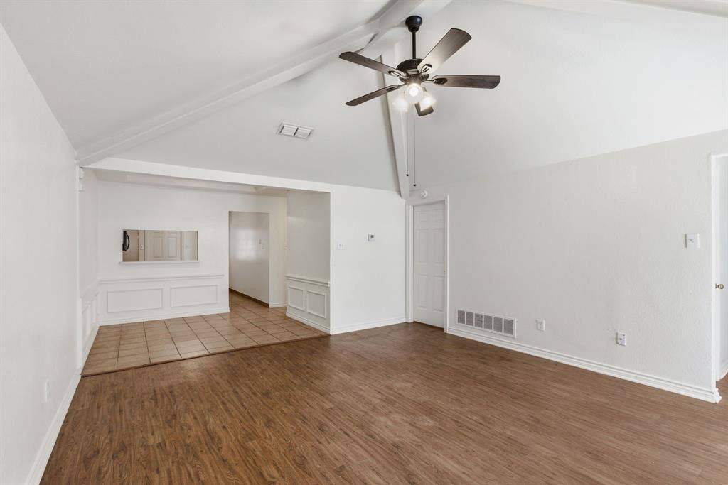 Vaulted ceilings with exposed beams, wood-finish flooring, tile flooring, ceiling fan with integrated lighting, and wainscoting