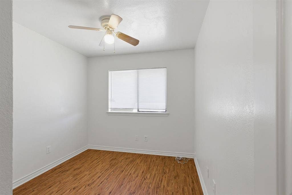 Wood-finish flooring, recessed window with blinds, and a ceiling fan with integrated lighting