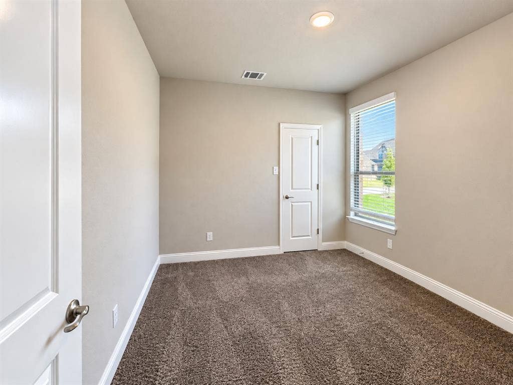 Wall-to-wall carpeting, recessed ceiling light, white paneled door, and a single window with blinds