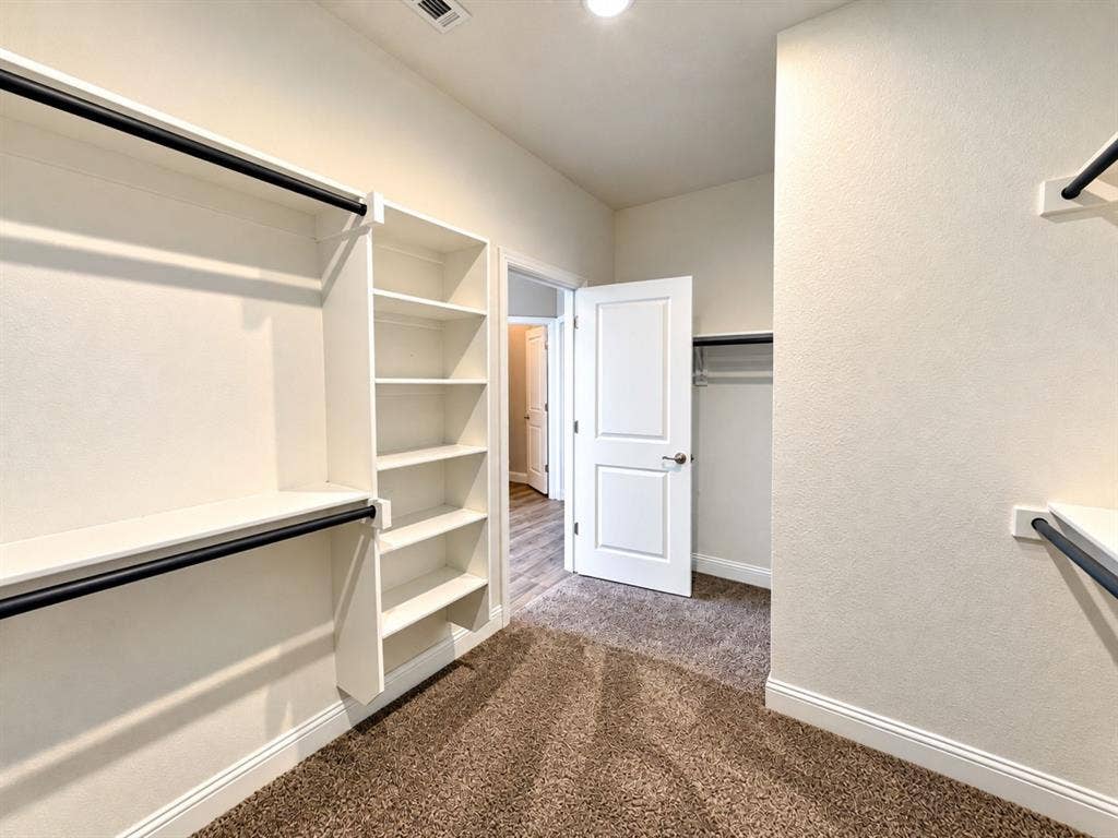 Integrated shelving, built-in clothing rods, white interior doors, and neutral carpeting