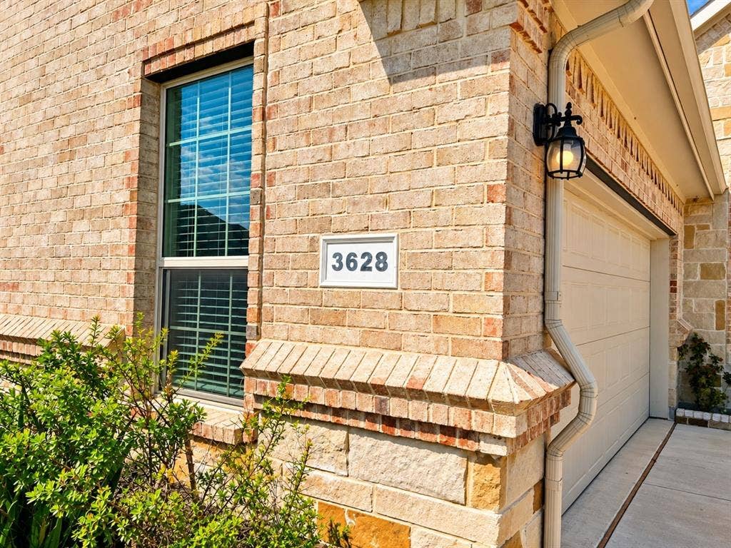 Brick exterior with stone accents, integrated garage, and exterior wall lantern