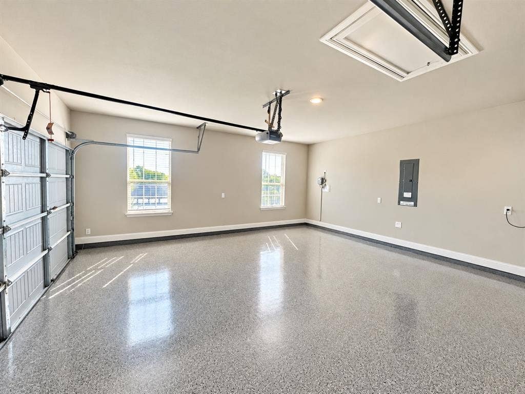 Expansive garage with a speckled epoxy floor finish, two windows, and overhead lighting