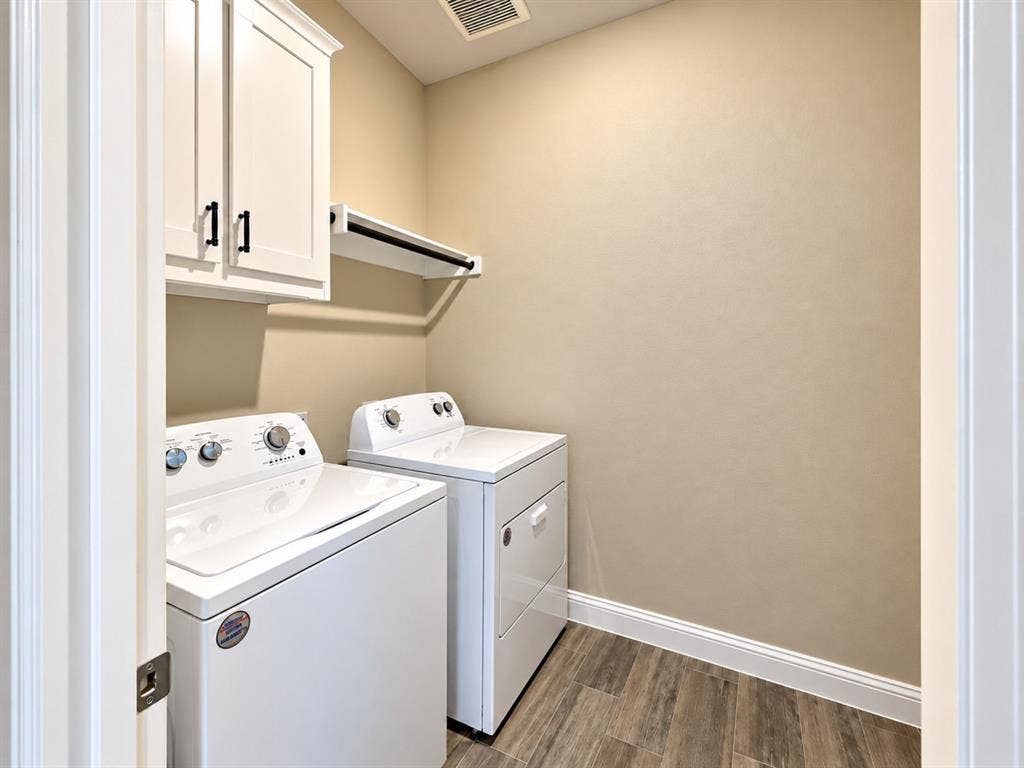 White shaker-style cabinetry with matte black hardware, wood-finish flooring, and a built-in hanging rod