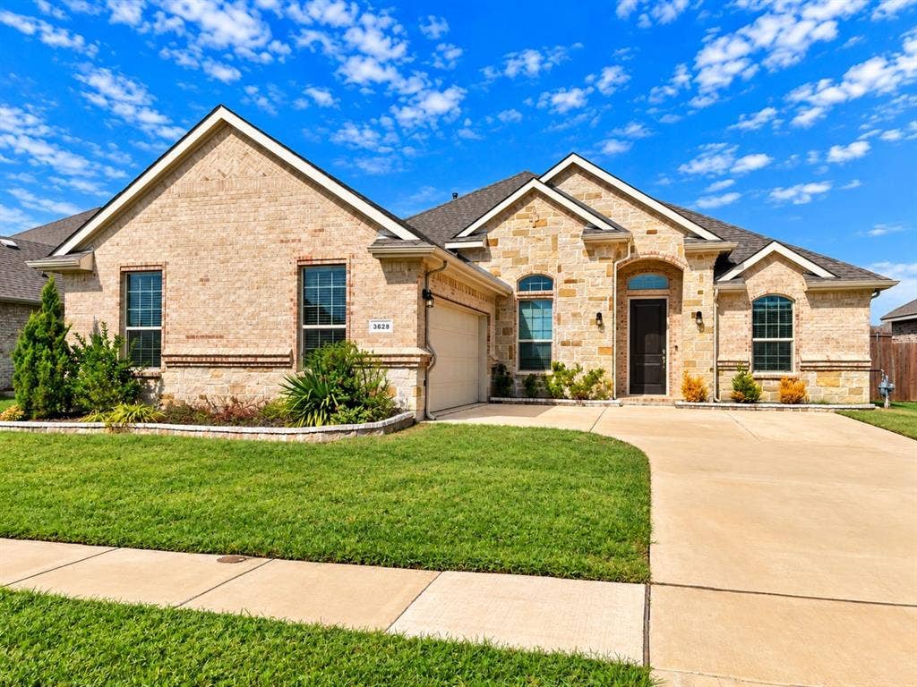 Elegant brick residence featuring a gabled roofline with multiple architectural peaks, arched entryway, and substantial windows throughout