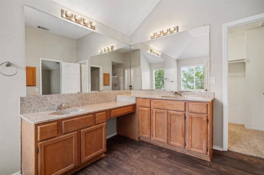 Primary bathroom offers corner vanity with dual sinks and a a powder area, walk in closet
