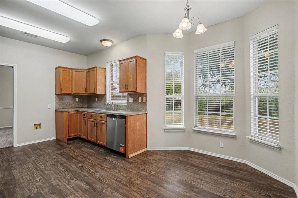 Open floorplan: View of stained kitchen cabinets, gas drop-in gas cooktop, wall oven and microwave opened to the family room.