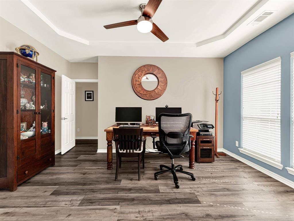 Tall windows wash the office’s blue accent wall and broad floor space with natural light. Enjoy a productive morning working from home, with a sunny place to pause between tasks.