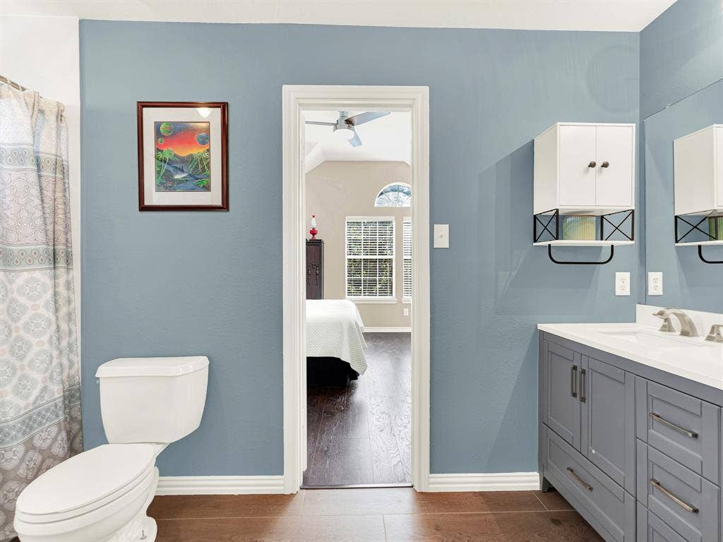 A gray vanity with a crisp white countertop brightens the bathroom, and a bedroom doorway creates a direct connection between the spaces. Ease through the morning routine before heading downstairs for breakfast.