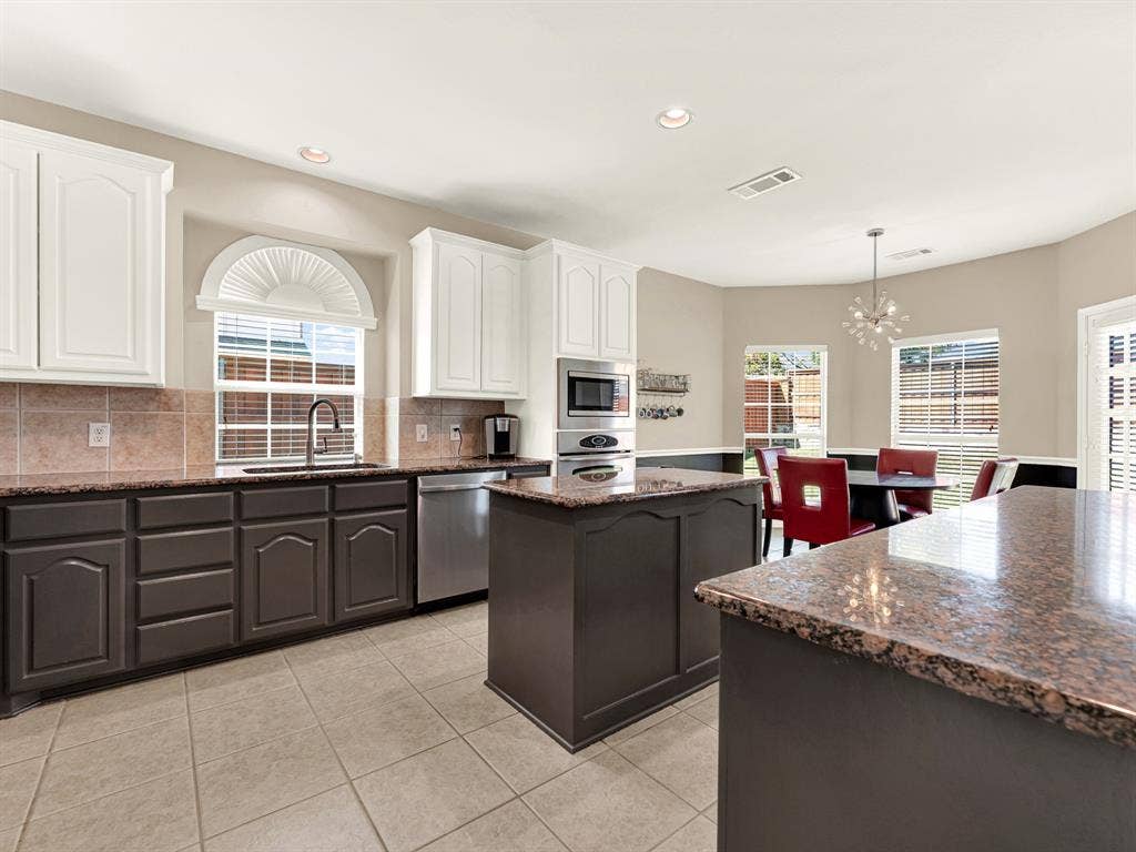 An arched window above the sink and additional windows around the breakfast area draw natural light across the kitchen. Ease into the day over breakfast, then step outside through the nearby backyard door.