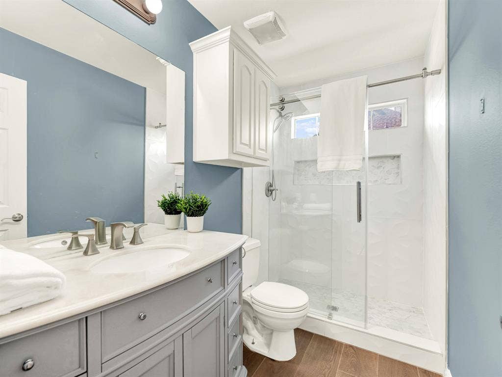 High shower windows illuminate dimensional white tile and a long recessed niche, while sliding glass doors preserve the bathroom’s sense of space. Rinse off after an afternoon outdoors and feel ready for the rest of the evening.