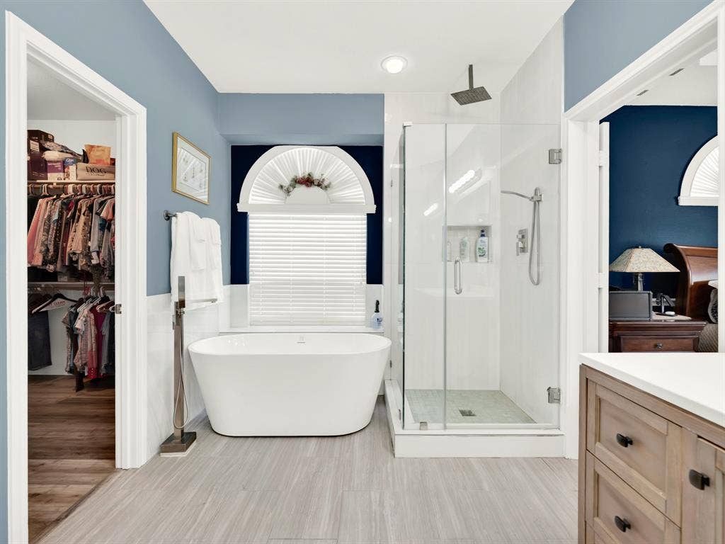 Clear glass keeps the shower visually open, revealing white tile, a recessed niche, and an overhead rainfall showerhead. Start the morning with a refreshing rinse before choosing your outfit from the adjacent closet.