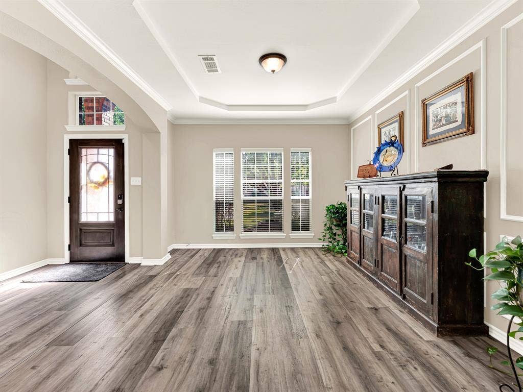 White picture-frame wall molding and crown trim lend quiet detail to the front room, catching soft shadows throughout the day. Create a welcoming spot for an evening puzzle and a little friendly competition.