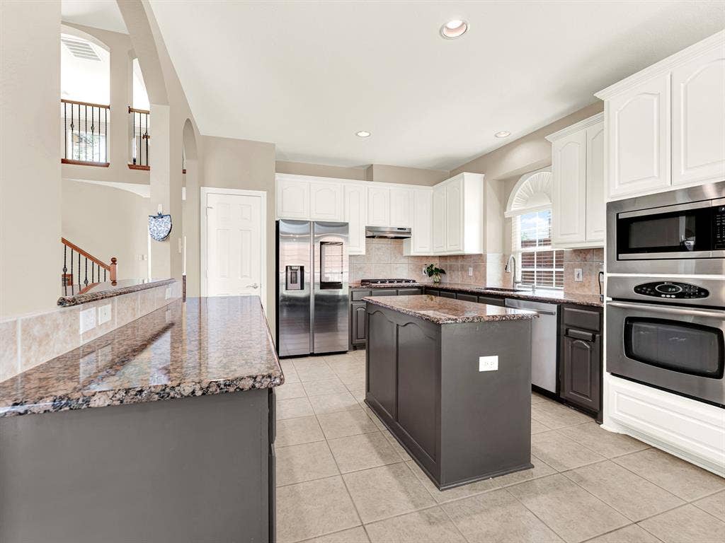 A granite-topped island anchors the kitchen, with generous counters offering plenty of room to spread out beneath recessed lighting. Picture preparing a weekend brunch together, with space for everyone to lend a hand.