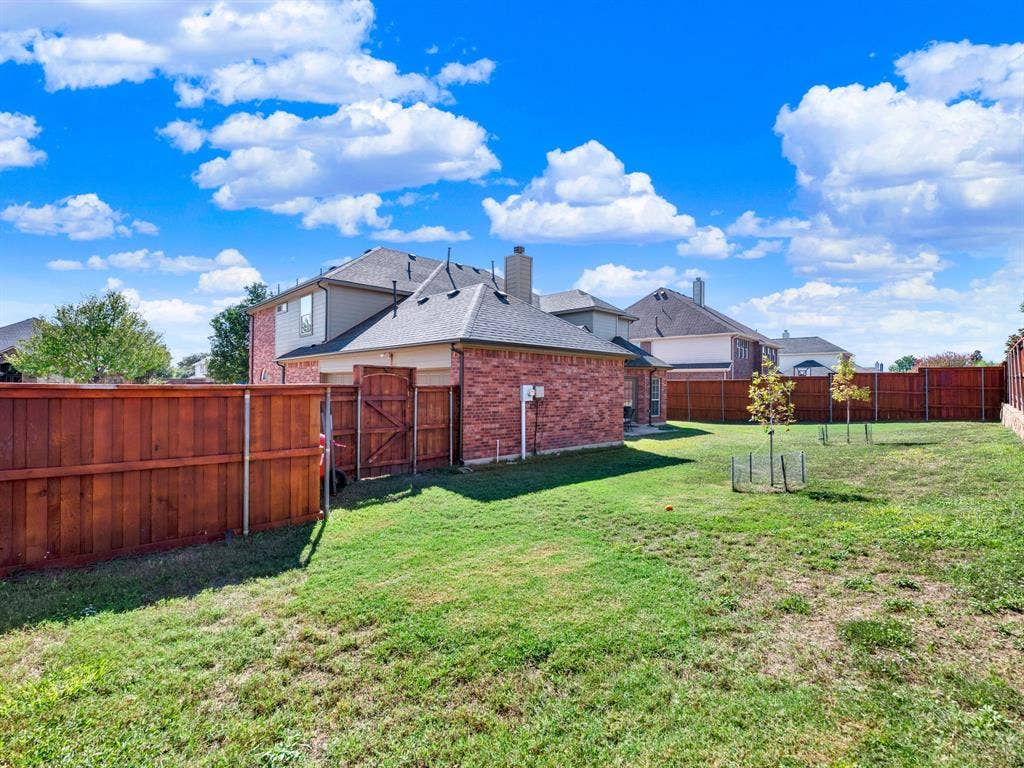 A richly stained wood fence wraps the broad yard, defining an outdoor retreat with room for both sunny planting beds and open grass. Spend a weekend morning tending your garden before enjoying lemonade with friends.