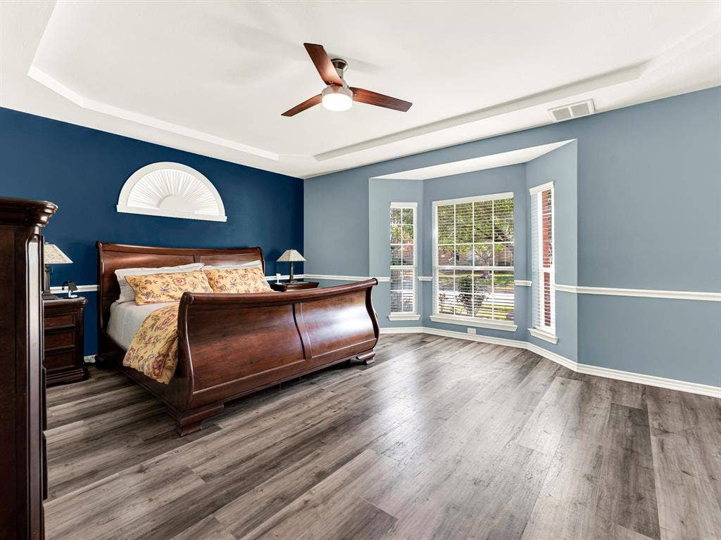A deep window bay expands the primary bedroom, drawing sunlight across the floor and framing views of the trees outside. Take a few unhurried minutes to stretch in the morning before the day begins.