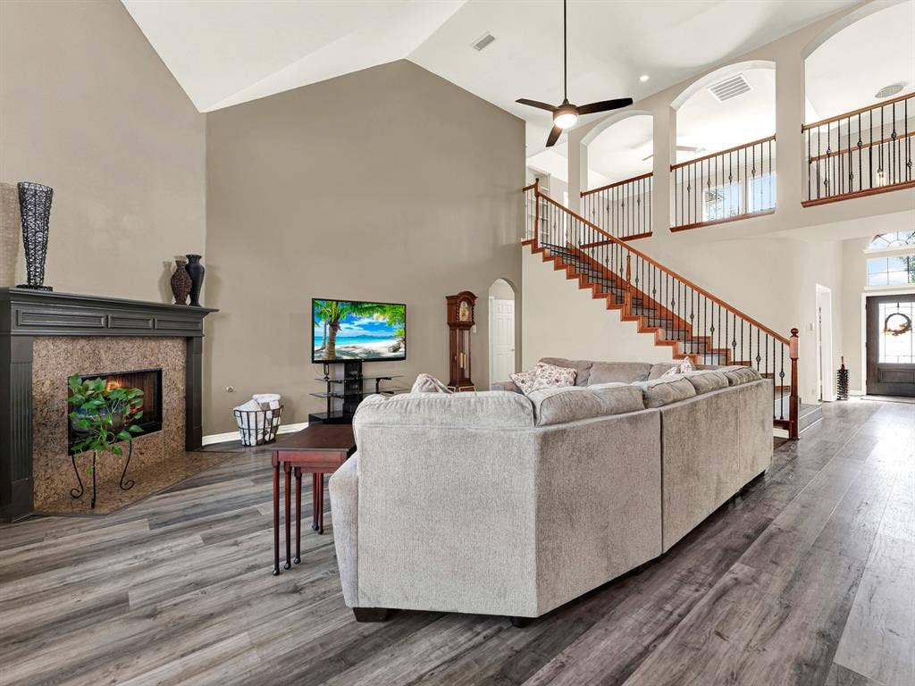 The sweeping staircase pairs warm wood tones with slender metal balusters, creating an airy connection to the upstairs landing. When temperatures dip, gather beside the fireplace for a quiet evening of conversation.