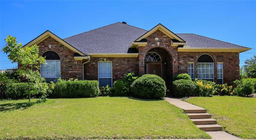 Brick exterior with architectural shingles, arched entryway, and multiple windows