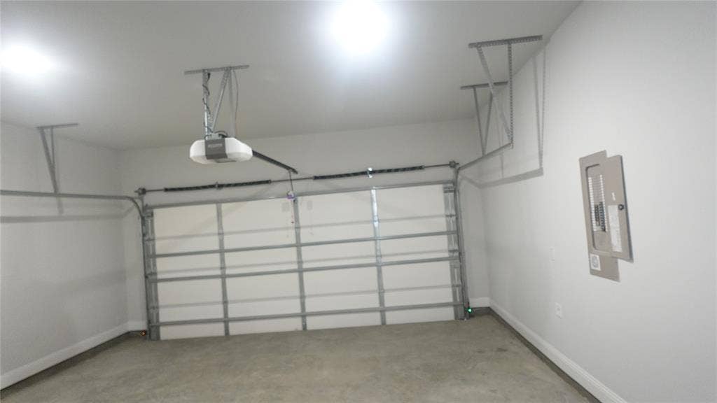 Garage featuring a concrete floor, white walls, and an automatic garage door opener