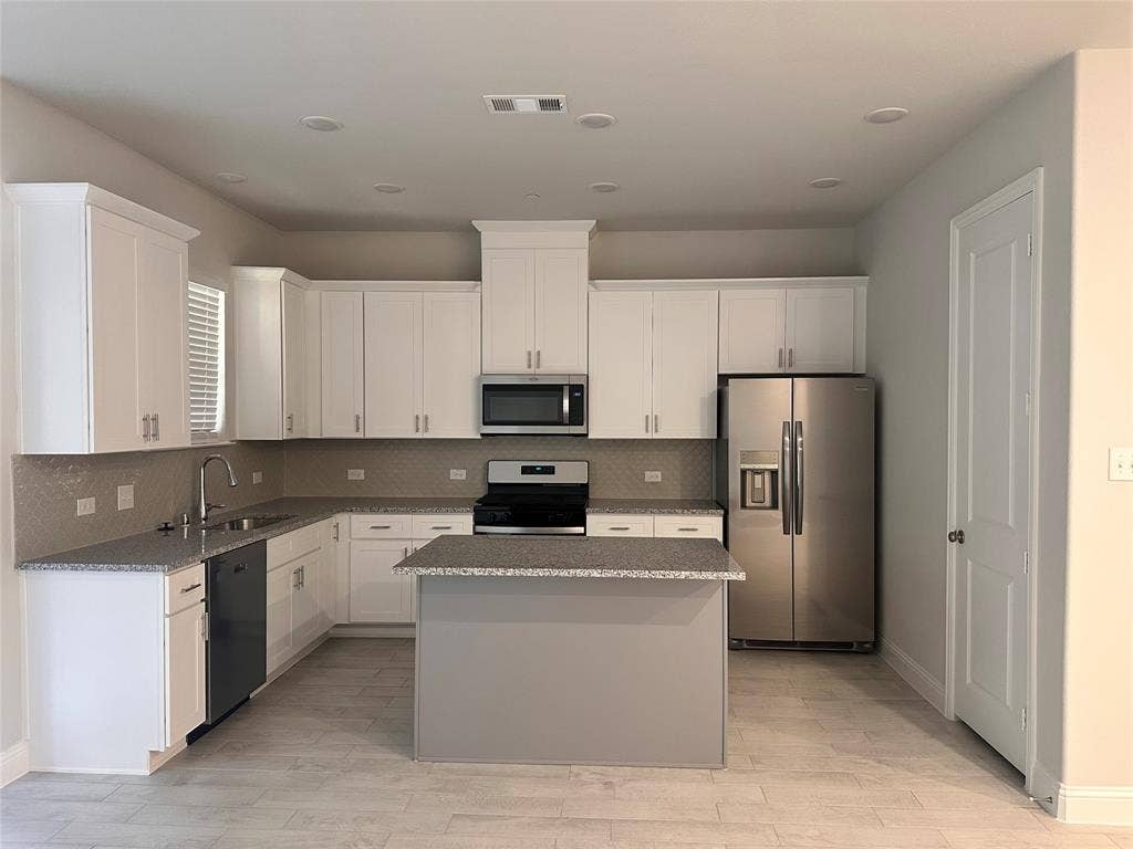 Kitchen featuring white cabinetry, stainless steel appliances, a center island, and wood-finish flooring