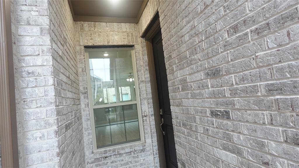 Brick exterior with a window featuring grilles and a dark-framed entry door