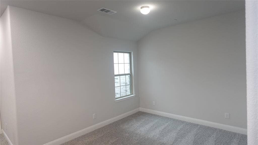 Neutral wall paint, ceiling-mounted light fixture, single window, and gray carpet flooring