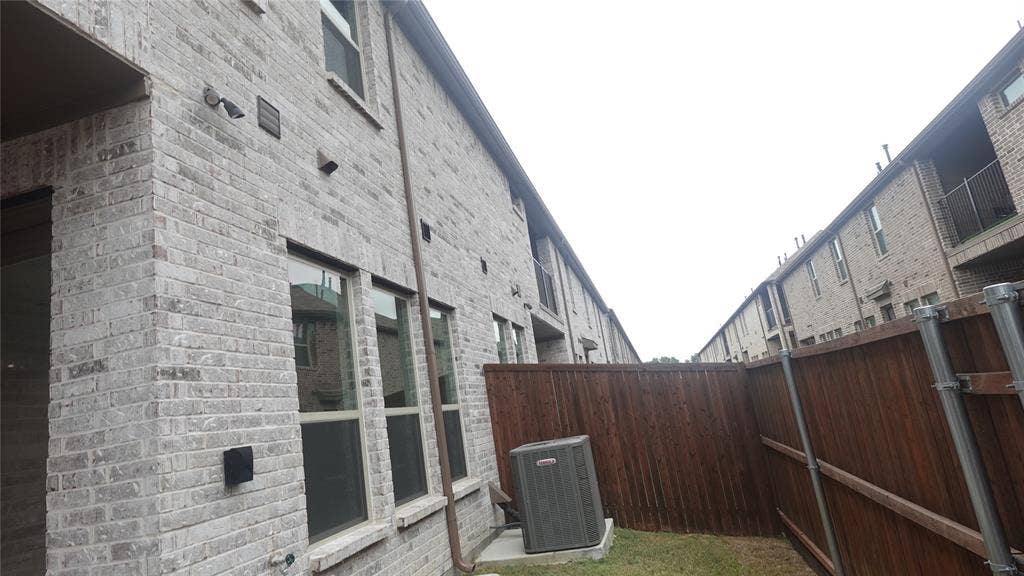 Brick exterior with multiple windows and a wood fence