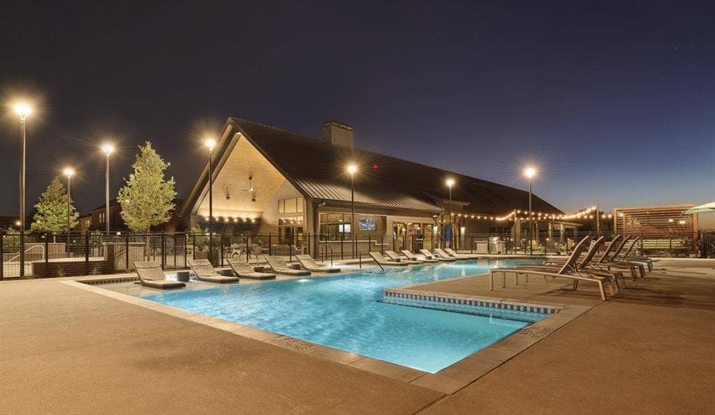 Pool at twilight featuring a patio and a community pool