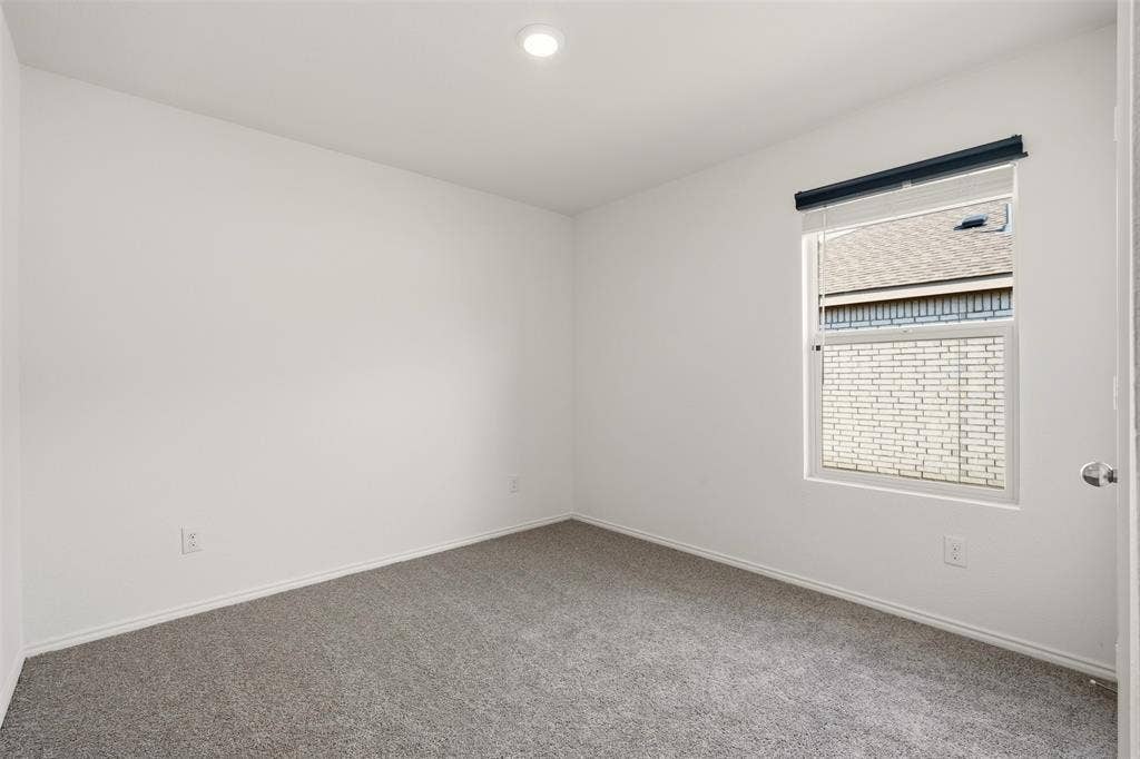 Recessed ceiling lighting, neutral carpeting, and a window with blinds