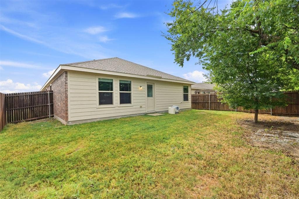 Expansive backyard with a full privacy fence, mature trees, and a brick and siding exterior