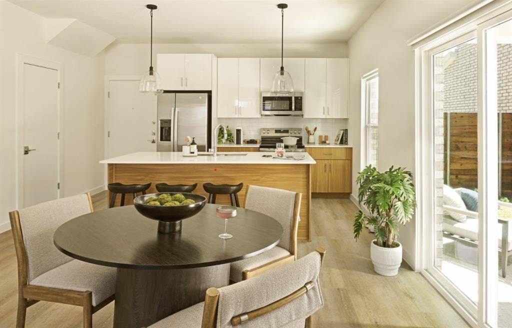 Kitchen featuring stainless steel appliances, light wood finished floors, tasteful backsplash, a center island with sink, and light countertops