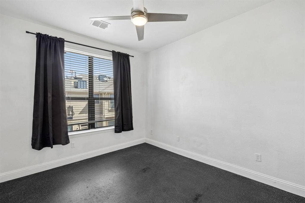 Window with horizontal blinds, overhead ceiling fan, and dark carpeting