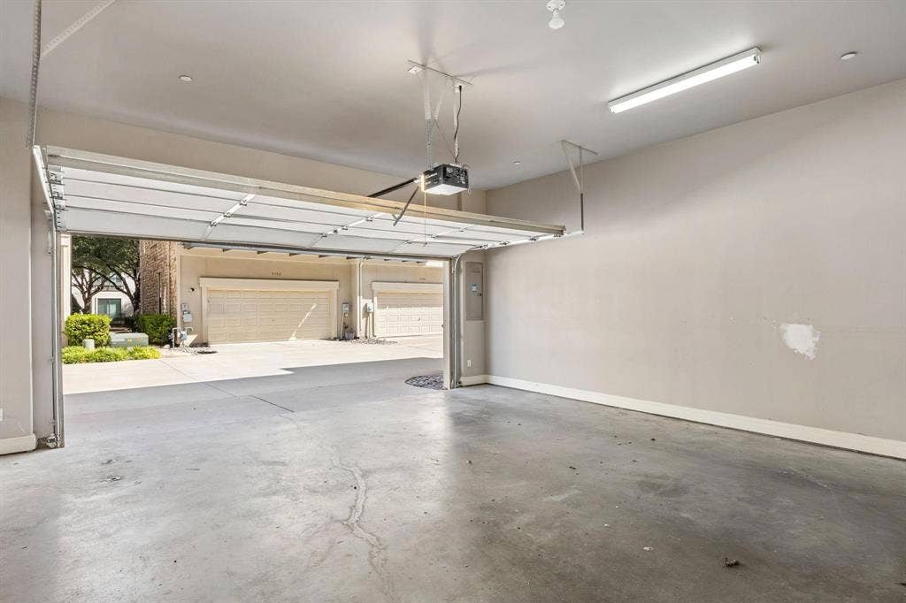 Attached garage with a concrete floor, automatic garage door opener, and fluorescent lighting
