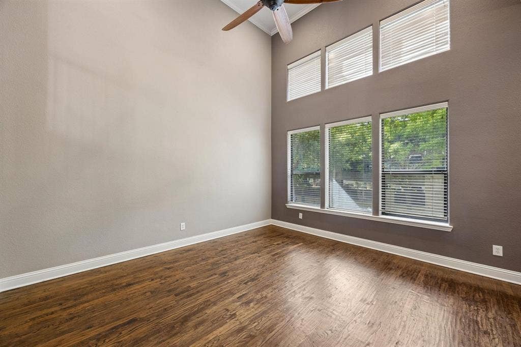 Vaulted ceiling with a ceiling fan, wood-finish flooring, multiple windows with blinds, and white baseboards