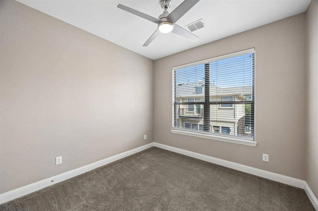 Neutral tone walls, ceiling fan with integrated lighting, window with blinds, and carpeted flooring