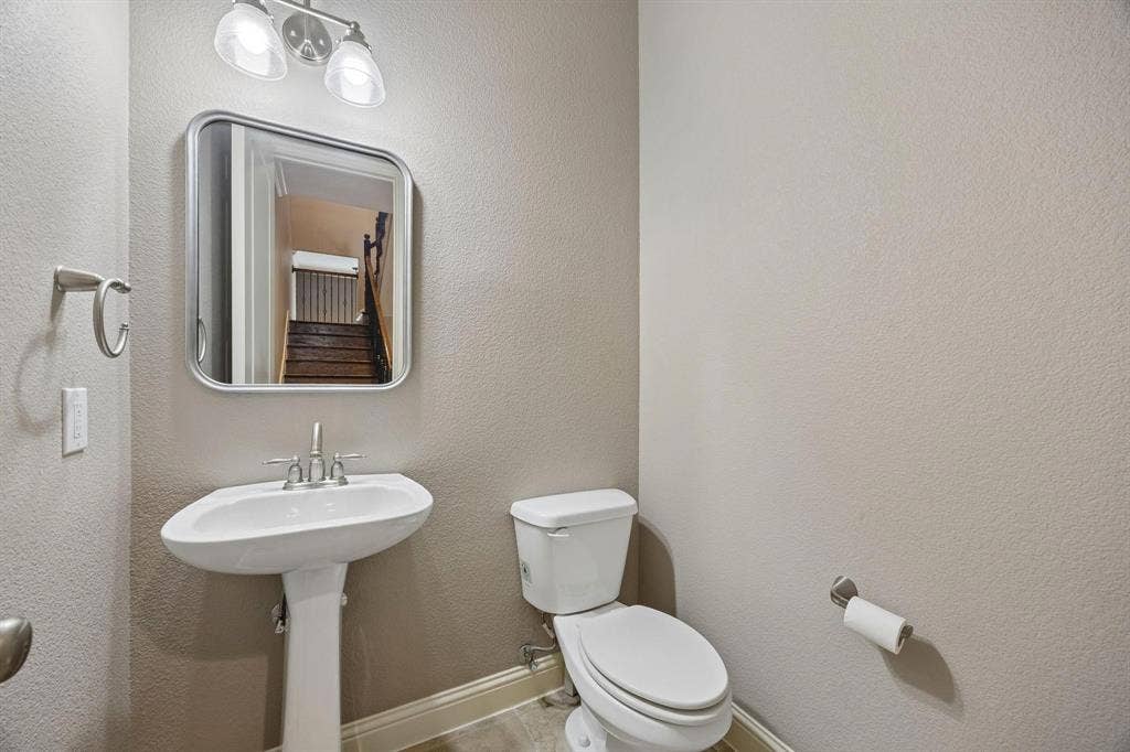 Pedestal sink with a polished chrome faucet, rectangular framed mirror, and two-light vanity fixture