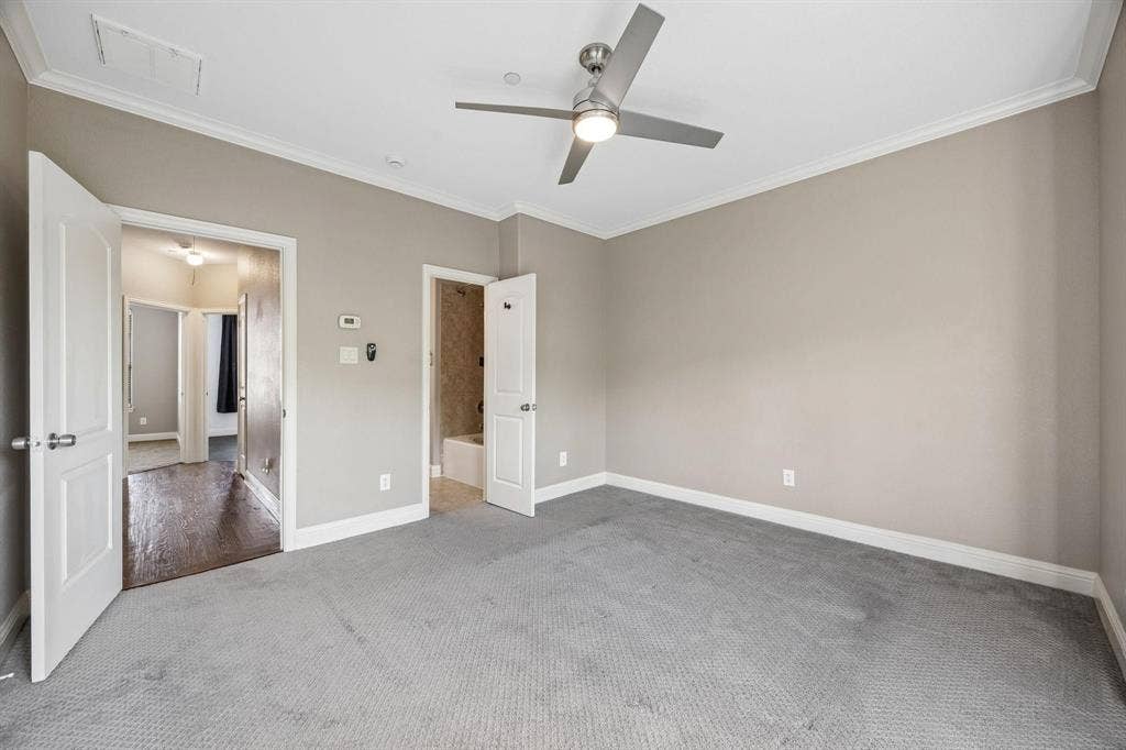 Spacious room featuring neutral-toned walls, crown molding, and a contemporary ceiling fan with integrated lighting