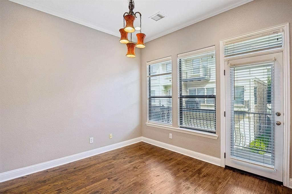Wood-finish flooring, white trim, multiple windows, a glass-paned door, and a built-in light fixture