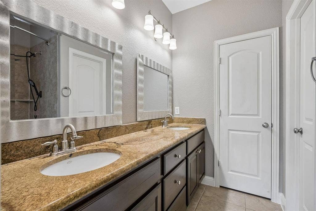 Dual vanity with under-mount sinks, a stone-finish countertop, and dark wood-finish cabinetry