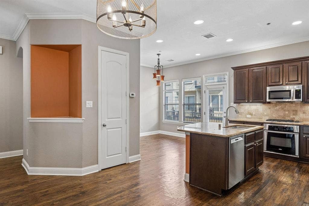 Open-concept kitchen with wood-finish flooring, dark wood cabinetry, and stainless steel appliances