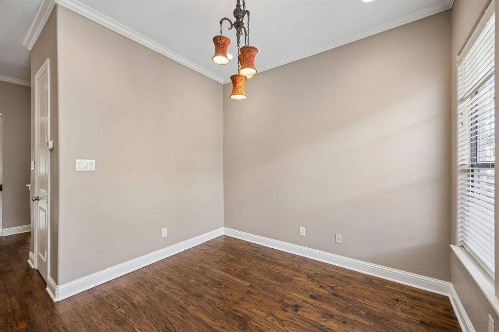 Wood-finish flooring, crown molding, a built-in window with blinds, and an overhead decorative light fixture