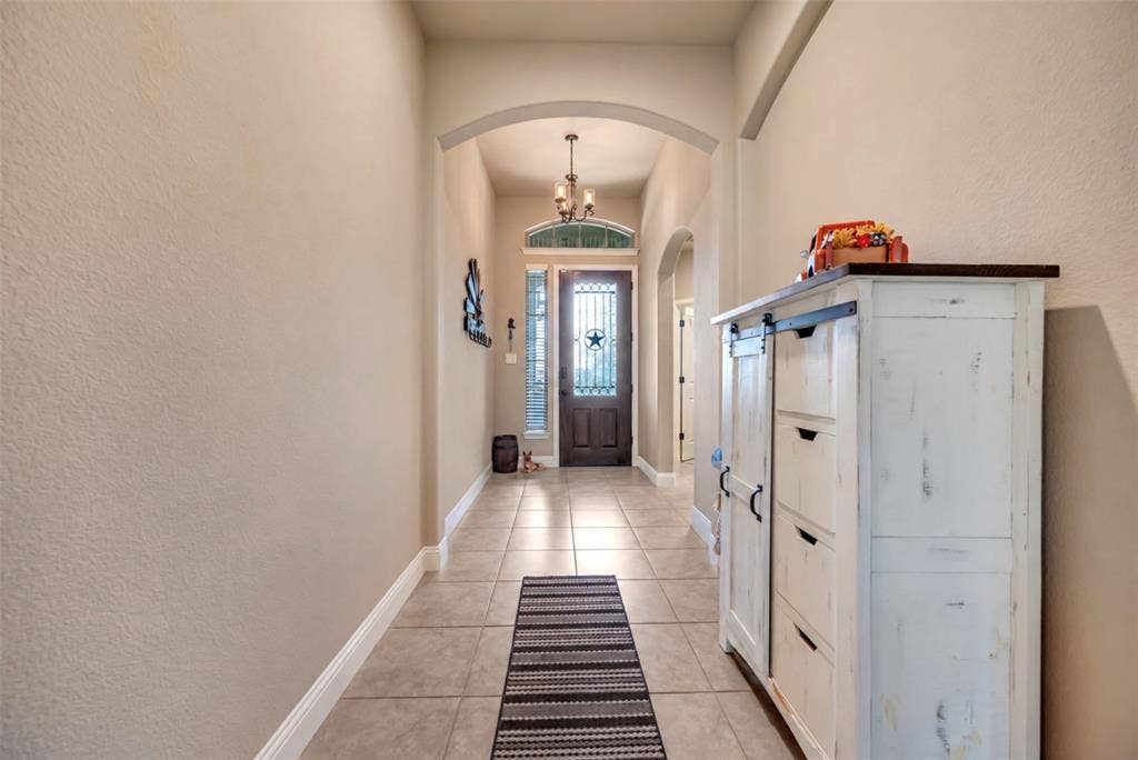 Foyer featuring large-format ceramic tile flooring, arched architectural detailing, high ceilings, an iron-accented front door, and a transom window