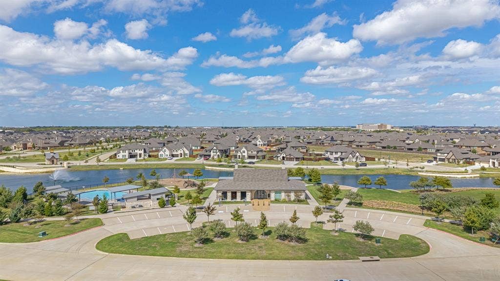 Community amenity center featuring a swimming pool, clubhouse, water feature, and dedicated parking