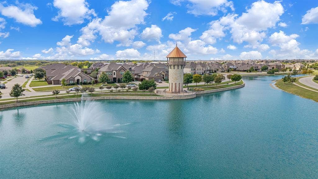 Expansive waterfront setting featuring a decorative water fountain, a stone-clad architectural tower, and stone retaining walls