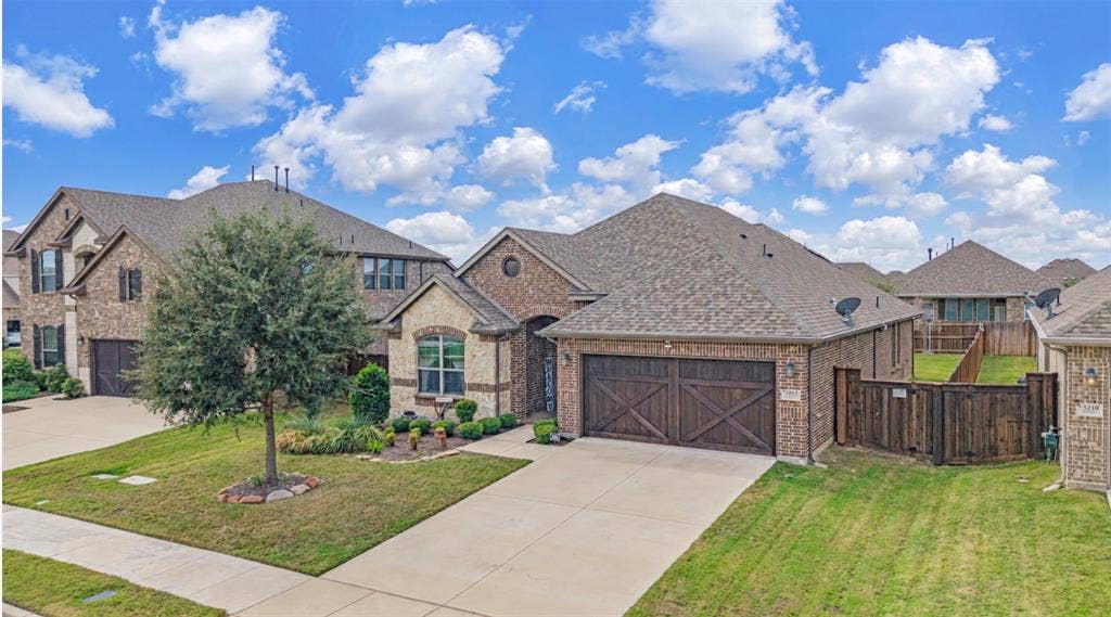 Brick exterior featuring a multi-gabled roofline, a decorative round accent window, and a wood-finish carriage-style garage door