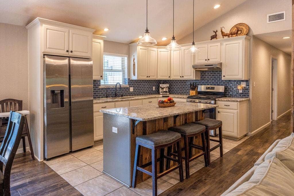 384 Fort Graham Road, Waco, TX 76705 Kitchen featuring white cabinetry, a large kitchen island with counter seating, stainless steel appliances, a dark tile backsplash, and recessed lighting