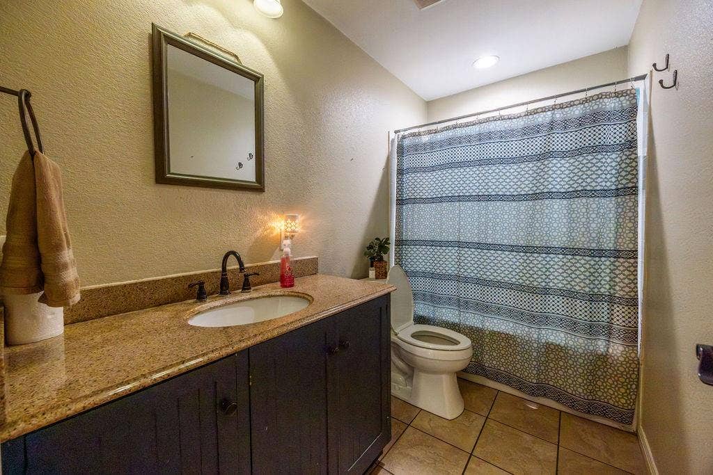384 Fort Graham Road, Waco, TX 76705 Vanity with an integrated sink, dark wood-finish cabinetry, and a stone-finish countertop