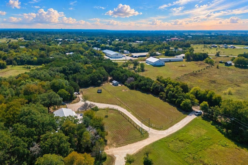 384 Fort Graham Road, Waco, TX 76705 Expansive property featuring a white-roofed building, multiple outbuildings, and a gravel drive