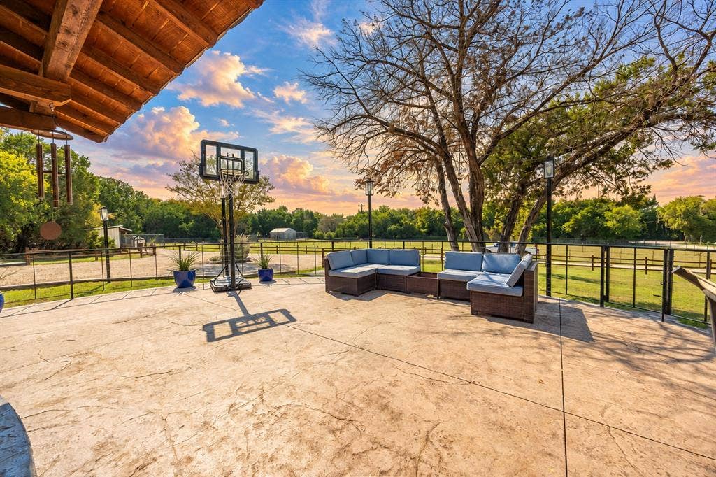 384 Fort Graham Road, Waco, TX 76705 Expansive stamped concrete patio with an exposed wood beam overhang and black metal fencing
