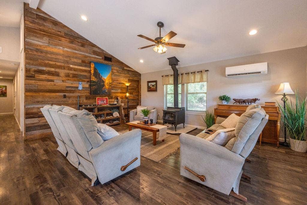 384 Fort Graham Road, Waco, TX 76705 Vaulted ceiling with recessed lighting, wood-finish flooring, wood plank accent wall, wood-burning stove, and ceiling fan with light fixture